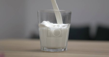 Téléchargez les photos : Verser le lait dans le verre, en insistant sur la texture crémeuse et riche en protéines - en image libre de droit