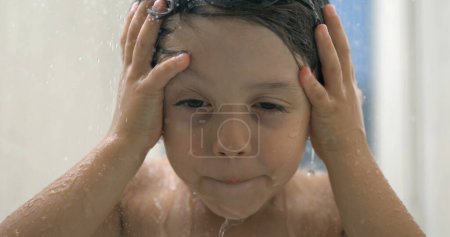 Téléchargez les photos : Douche pour enfants en super ralenti, gouttelettes d'eau en cascade et éclaboussures pendant le bain, lavage de la tête et des cheveux des enfants avec les mains en 800 ips - en image libre de droit