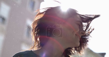 Photo for Carefree woman shaking hair in super slow-motion outside in the sunlight with flare. 800 fps clip of 30s adult girl shakes head sideways - Royalty Free Image