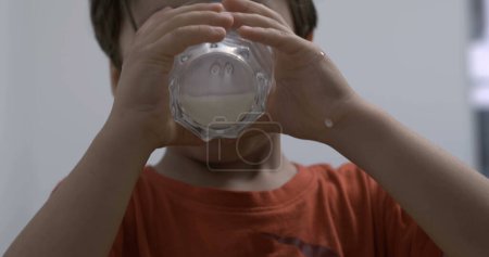 Téléchargez les photos : Jeune garçon buvant du lait tenant tasse en verre. Aliments riches en protéines pour enfants - en image libre de droit