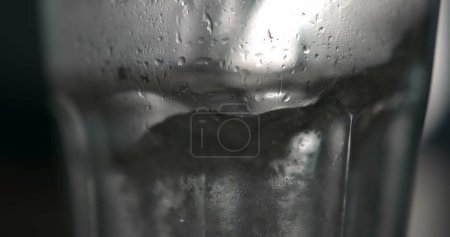 Téléchargez les photos : Eau bouillonnante Saupoudrer sur la surface en super ralenti, Verser une boisson rafraîchissante dans une tasse en verre transparent - en image libre de droit