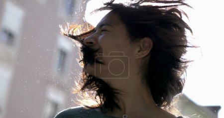 Foto de Mujer despreocupada sacudiendo el cabello en cámara súper lenta afuera a la luz del sol con bengalas. 800 fps clip de 30 años chica adulta sacude la cabeza hacia los lados - Imagen libre de derechos