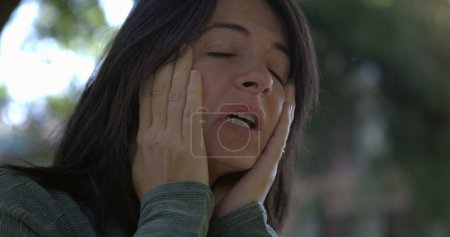 Foto de Mujer estresada sintiendo ansiedad y angustia mientras frota la cara en cámara lenta 800 fps. Cara de cerca de la persona femenina en los años 30 sintiendo dolor y nerviosismo - Imagen libre de derechos