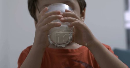 Foto de Niño bebiendo leche sosteniendo una taza de vidrio. Alimentación infantil alimentos ricos en proteínas - Imagen libre de derechos