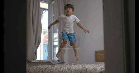 Téléchargez les photos : Jeune garçon sautant jubilement sur le lit, 800 ips vitesse rampé ultra ralenti - en image libre de droit