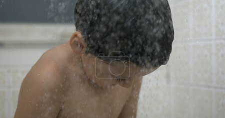 Téléchargez les photos : 800fps au ralenti - Scène de bain rêveuse avec des gouttelettes éclaboussant la tête de l'enfant, routine de lavage éthérée des enfants - en image libre de droit