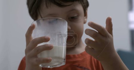 Foto de Niño bebiendo leche sosteniendo una taza de vidrio. Alimentación infantil alimentos ricos en proteínas - Imagen libre de derechos
