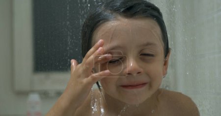 Photo for Close-up young boy's face underneath shower head with water pouring in slow-motion 1000 fps, bath time routine - Royalty Free Image
