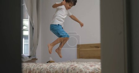 Photo for Excited happy child jumping up and down in bed in slow-motion. 1000 fps clip of little boy bouncing in bedroom - Royalty Free Image