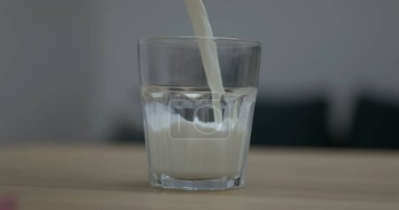 Photo for Pouring milk into glass cup in super slow-motion 800 fps, refreshing protein-rich drink - Royalty Free Image