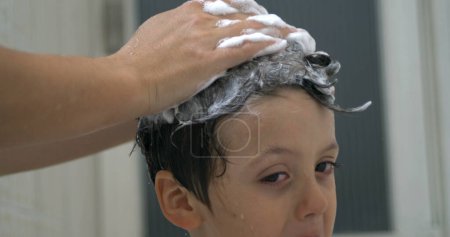 Photo for Close-up parent hand rubbing child's head with shampoo during bathtime routine in slow-motion 800 fps, speed ramp - Royalty Free Image