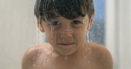 Téléchargez les photos : Capture au ralenti superbe de 800ips du visage de l'enfant heureux entouré de gouttelettes de douche - en image libre de droit