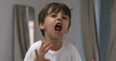 Foto de Niño enojado gritando y gritando a la cámara en cámara súper lenta. Niño caucásico trastornado en modo rabieta - Imagen libre de derechos
