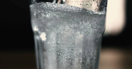 Téléchargez les photos : Servir l'eau saupoudrer dans une tasse en verre transparent en 800 ips au ralenti. Bulles bulles en surface - en image libre de droit