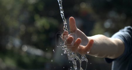 Photo for Close-up child hand in water fountain captured in high-speed 800 fps slow-motion. Refreshing liquid droplets, washing hands during hot day - Royalty Free Image