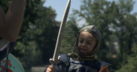 Téléchargez les photos : Enfant en costume d'époque s'engageant dans le jeu d'épée - en image libre de droit