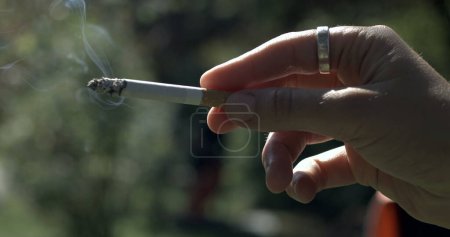 Téléchargez les photos : Gros plan main tenant cigarette capturée - en image libre de droit