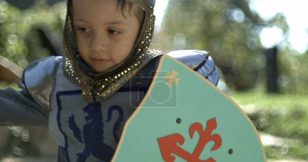 Photo for Little boy wearing traditional medieval costume hitting with sword and holding shield captured , speed ramp - Royalty Free Image
