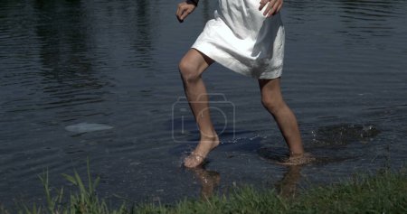 Foto de Primer plano piernas de niña corriendo y salpicando en el agua del estanque capturado con una cámara de alta velocidad - Imagen libre de derechos