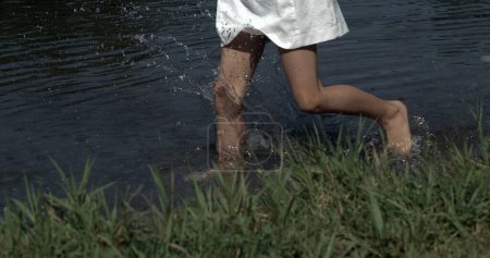 Photo for Close-up little girl legs running and splashing in pond water captured with a high-speed camera - Royalty Free Image