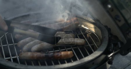 Photo for Sausages Sizzling on BBQ Grill ?Smoky Barbecue Cooking Scene with Grilling Meat - Royalty Free Image
