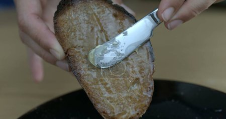 Téléchargez les photos : Couteau au beurre glissant miel sur pain grillé - en image libre de droit