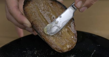 Foto de Esparcir miel en pan tostado con cuchillo de mantequilla - Imagen libre de derechos