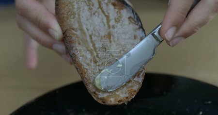Téléchargez les photos : Couteau au beurre glissant miel sur pain grillé - en image libre de droit