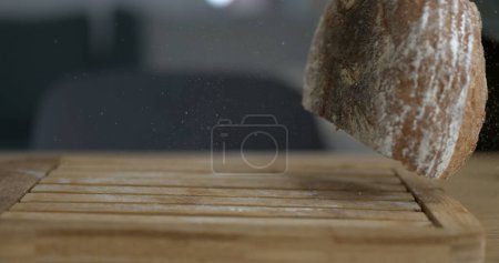 Téléchargez les photos : Chute de pain rustique traditionnel capturé avec caméra avec de la farine et des miettes volantes dans les airs - en image libre de droit
