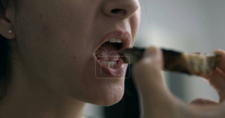 Photo for Savoring Slowly - Close-up of Woman Enjoying Toast. Person takes a bite of carb food - Royalty Free Image