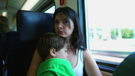 Téléchargez les photos : Mère et fils à bord d'un rapide voyage en train, maman introspective plongée dans une profonde contemplation - en image libre de droit