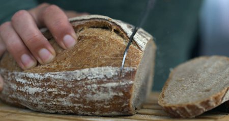 Foto de Trozo de pan en rodajas con cuchillo con migas y harina volando en el aire - Imagen libre de derechos
