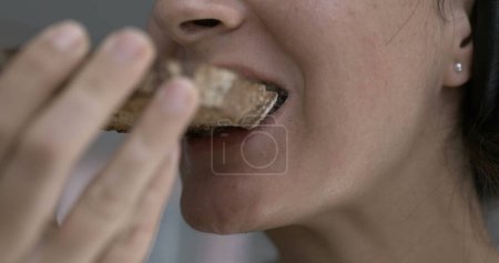Photo for Woman close-up mouth taking a bite of toast bread . Person eating carb food - Royalty Free Image