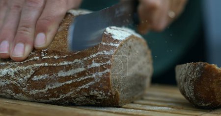 Photo for Capture of Bread Being Sliced with Flying Crumbs and flour with knife - Royalty Free Image