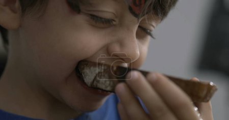 Téléchargez les photos : Un petit garçon prenant une bouchée de pain grillé, bouche d'enfant gros plan mangeant de la nourriture carb dans la rampe de vitesse - en image libre de droit