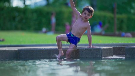 Foto de Niño que entra en la piscina durante el día de verano. Chico emocionado disfrutando de vacaciones - Imagen libre de derechos