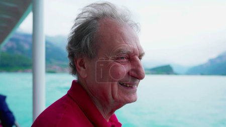 Photo for Joyful senior man traveling by boat observing lake and mountain view while smiling and laughing. Carefree Elderly person enjoying retirement exploring new horizons - Royalty Free Image