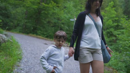 Téléchargez les photos : Mère et enfant se tenant la main marchant dans le sentier en forêt. Maman et son fils randonnée en plein air, week-end activité familiale, concept de voyage aventureux - en image libre de droit
