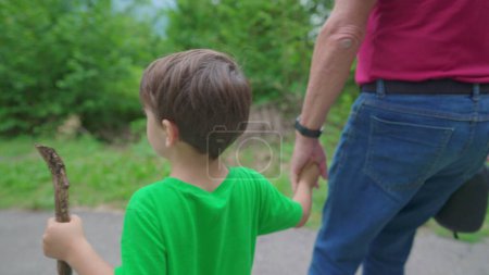 Photo for Family weekend activity scene of grandson holding hands with grandparent while hiking in nature. 4 year old boy with his grandfather in trail path - Royalty Free Image