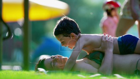 Téléchargez les photos : Moment d'amour sincère entre la mère et l'enfant posé sur l'herbe pendant l'activité de jour d'été, petit garçon voulant embrasser maman, moment tendre authentique - en image libre de droit