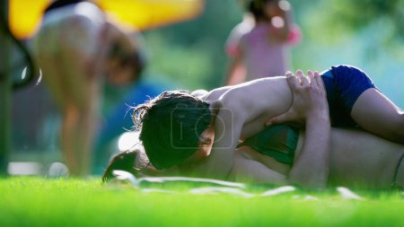Foto de Candid momento de amor entre la madre y el niño acostado en la hierba durante la actividad del día de verano, niño pequeño que quiere besar a la madre, momento tierno auténtico - Imagen libre de derechos