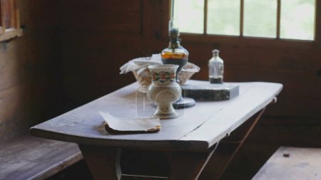 Photo for Traditional rustic ambience, rural furniture on display at farmhouse. Objects on display at wooden table by window - Royalty Free Image