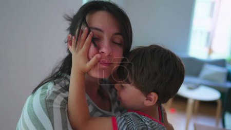 Téléchargez les photos : Mère et enfant dans l'étreinte chaude, partageant un véritable moment d'amour comme fils embrasse maman dans la joue - en image libre de droit