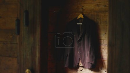 Téléchargez les photos : Ancien costume rural traditionnel suspendu par un mur en bois au chalet rustique dans les alpines exposées, ambiance antique - en image libre de droit