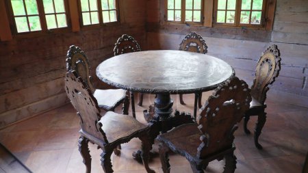 Photo for Rustic ancient wooden table and chairs inside traditional chalet farmhouse. Handmade furniture in alpine setting - Royalty Free Image