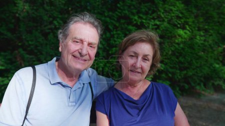 Téléchargez les photos : Portrait de couple de personnes âgées souriant à la caméra assis sur le banc du parc, visages rapprochés de personnes âgées heureuses, mari et femme dans les années 70 années de retraite - en image libre de droit