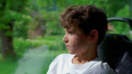 Foto de Niño reflexivo en el autobús, perdido en la mirada lejana. Viajero joven asentado en el asiento, exudando profunda reflexión seria expresión - Imagen libre de derechos