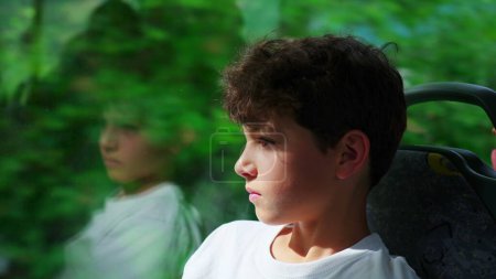 Photo for Close-up of contemplative preteen boy aboard bus, engrossed in scenic journey through window. Young male passenger in transport, showcasing introspective demeanor - Royalty Free Image