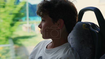 Photo for Pensive Teenager Observing Views from Bus Window, Young Boy Engrossed in Daydream During Ride - Royalty Free Image