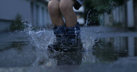 Photo for Joyful Splash - Kid in Rainboots Reveling in the Delight of Jumping into Puddles, Captured in Slow-Motion by High-Speed Camera - Royalty Free Image